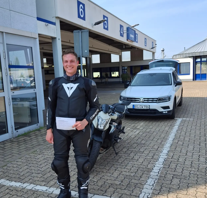 Fahrschüler mit Motorrad und Führerschein nach bestandener Prüfung